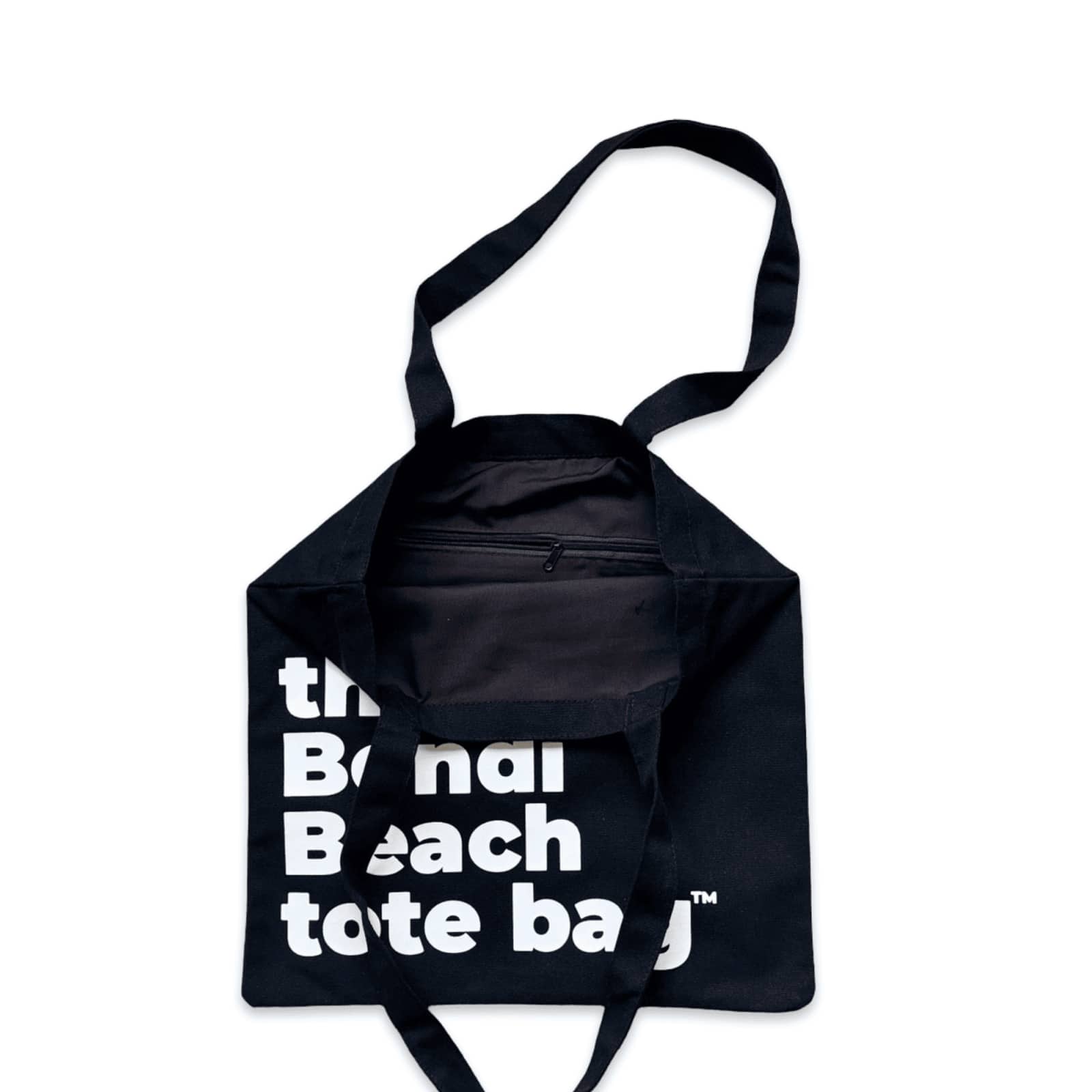The Bondi Beach tote bag Little Bondi in black with white print open showing zip pocket and lining