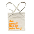 The Bondi Beach tote bag Little Bondi in off white with orange print flatlay closed showing slim canvas structure