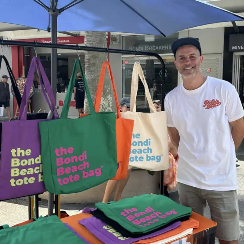 Adam at the Better Totes market stall in Bondi, bags hanging on the rack