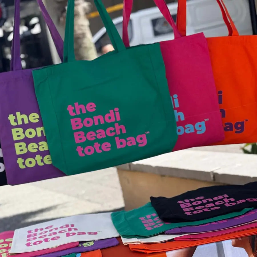 The rack of green, pink, orange and purple Bondi Beach totes at the market